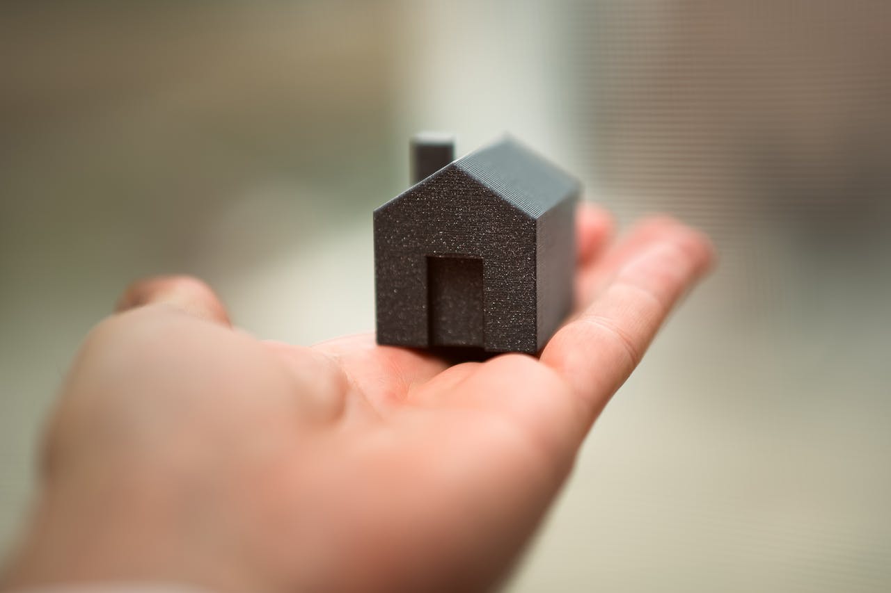 why-choose-us Close-up of a hand holding a miniature house model representing real estate concepts like buying or investment.